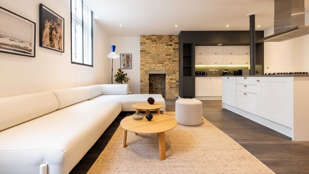 Un salon moderne avec un canapé blanc, une table basse ronde en bois et une cheminée.