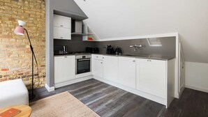 Eine moderne Küche mit weißen Schränken, einer Ziegelwand und einer Wohnzimmer-Decke.