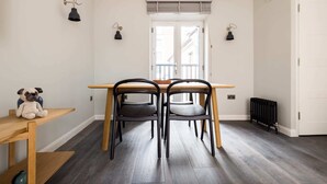 Ein Essbereich mit Holztisch und Stühlen, einem kleinen Tisch mit Stofftier sowie einer Fußbodenheizung.