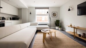 Ein modernes Wohnzimmer mit einer Couch, einem Couchtisch und einem an der Wand montierten Fernseher.