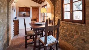 A rustic dining area with a wooden table and chairs, stone walls, and a window with a view of trees. - HAMLET THE POET - HOUSE SANTA LUCIA (Umbria)