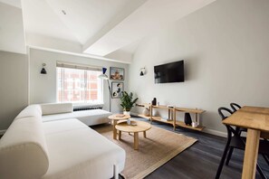 Un soggiorno moderno con un divano bianco, un tavolo da pranzo in legno e una TV a parete.