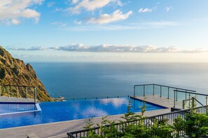 A pool with a view of the ocean and a rocky cliff. - Modern villa, shared infinity pool | SunsetCliff 7 (Faja Da Ovelha)