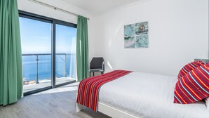 A bedroom with a large window, a bed with striped pillows, and a chair. - Modern villa, shared infinity pool | SunsetCliff 7 (Faja Da Ovelha)