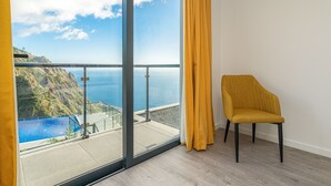 Une pièce dotée d’une grande porte-fenêtre coulissante donnant sur un balcon avec piscine et vue sur l’océan.