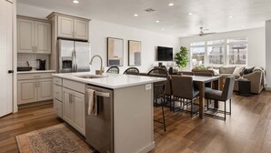 Una cocina moderna con una isla central, electrodomésticos integrados y una zona de comedor con un ventanal grande.
