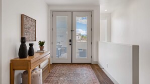 Un pasillo con un banco de madera, una alfombra y una puerta que da al exterior.