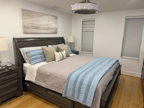 A bedroom with a bed, nightstands, a lamp, a painting, and a window with blinds. - Fort Myers Pool Home Near to Downtown & River District (Fort Myers)