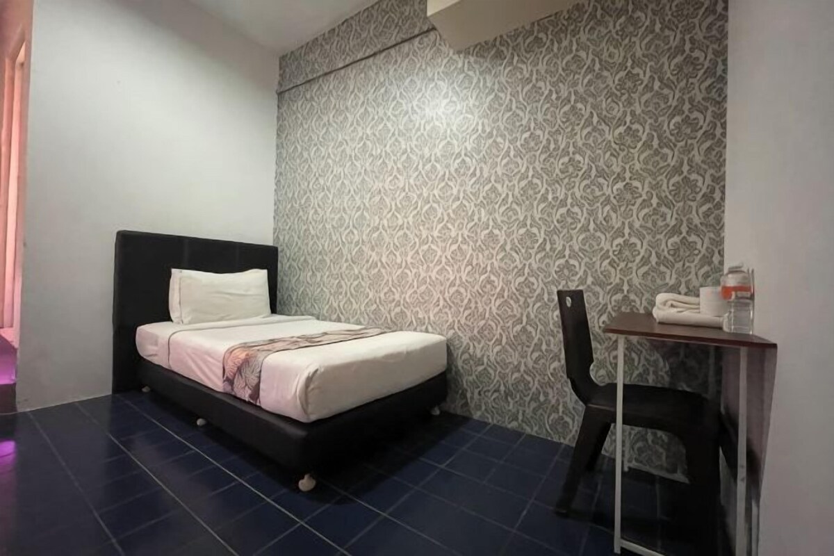 Een slaapkamer met een bed, een stoel, een tafel en een behang met patroon.
