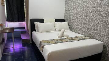Uma cama bem arrumada com roupa de cama branca e um manta estampada, uma pequena mesa de cabeceira com uma garrafa e uma xícara, e um papel de parede com padrão na parede adjacente.