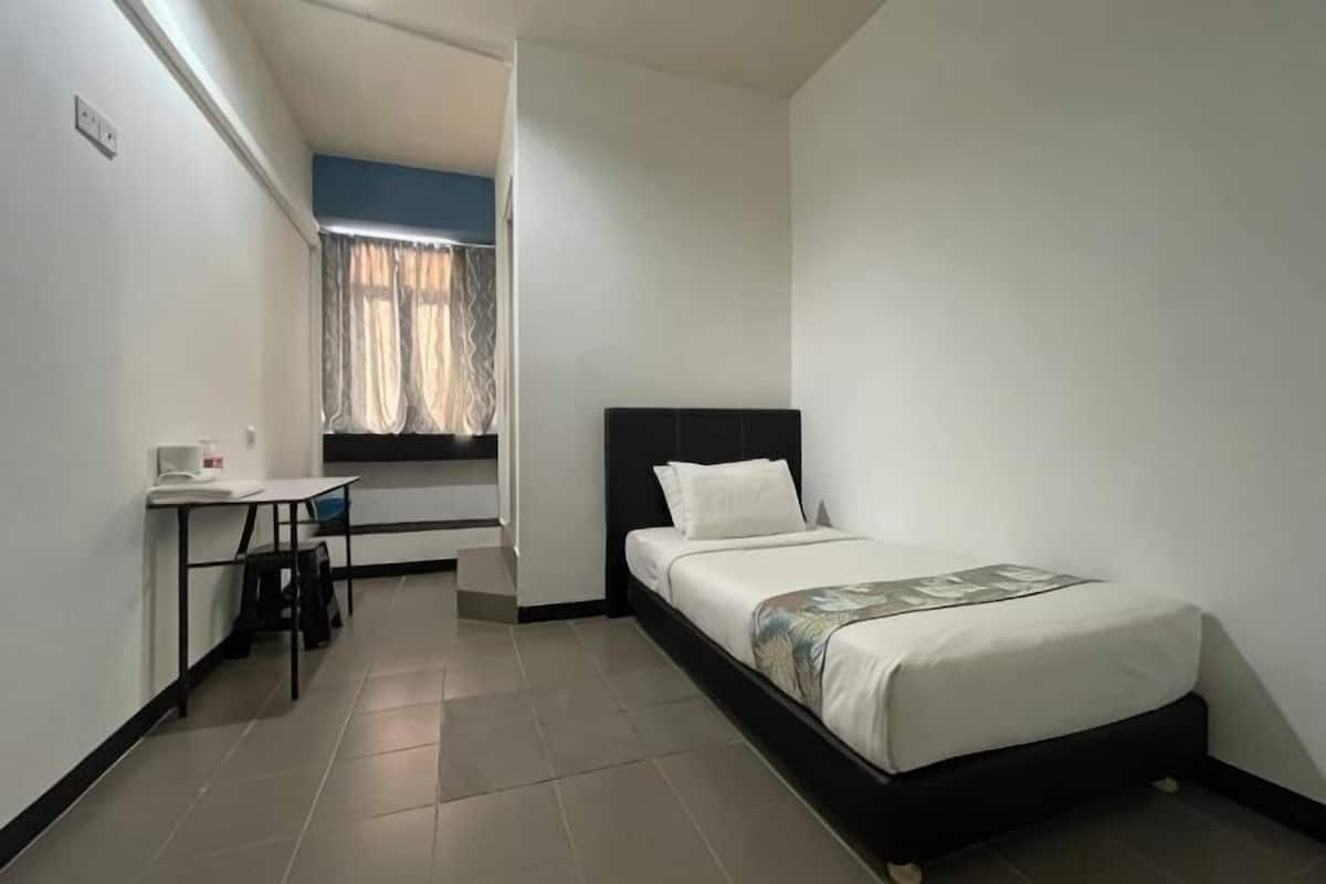 A small, clean room with a bed, a desk, and a window.