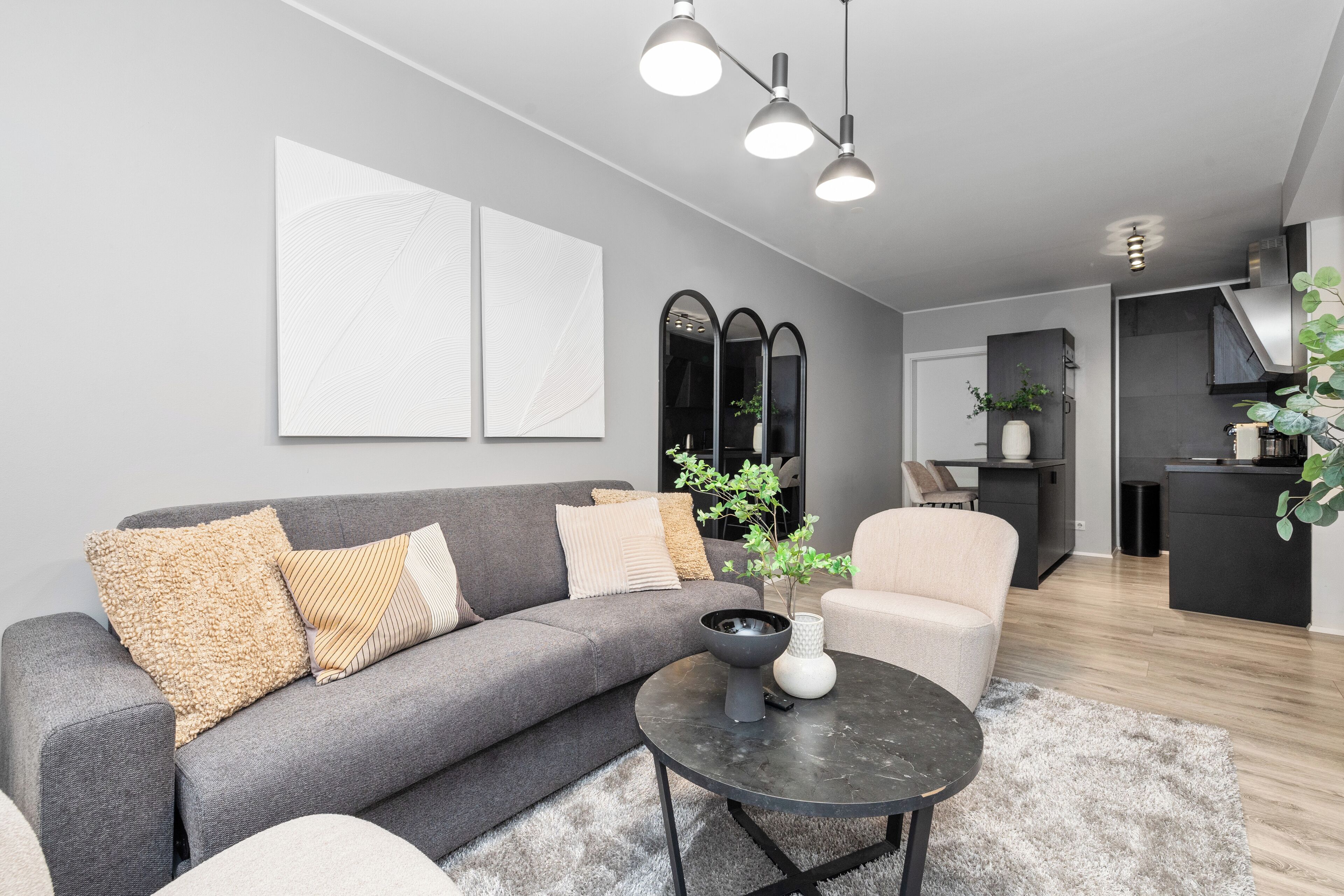 Een moderne woonkamer met een grijze bank, een ronde salontafel en een minimalistische inrichting.