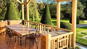 Eine Terrassengruppe im Freien mit Holztisch und -stühlen, umgeben von einer Holzpergola mit einer Laterne.