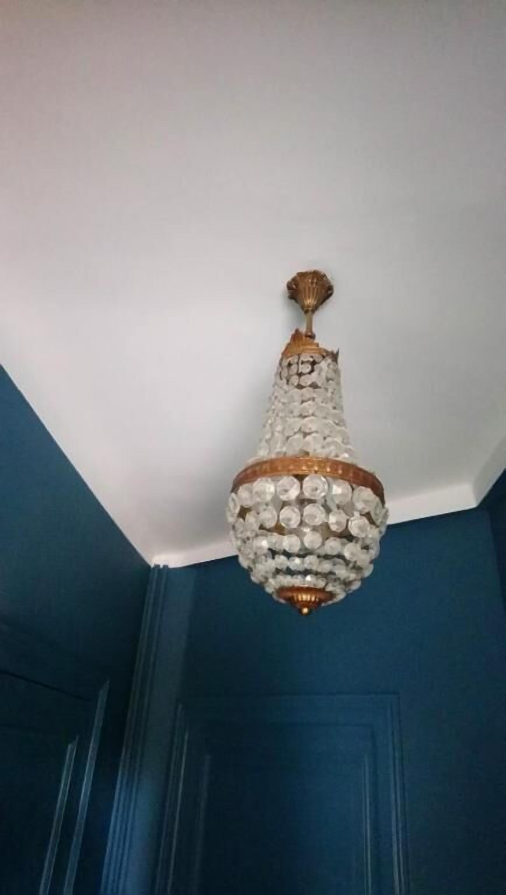 A chandelier with a crystal base and gold accents hanging from a white ceiling.
