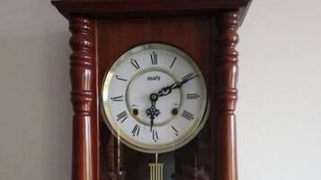 Une grande horloge à coucou en bois, fixée au mur, avec des chiffres romains et un balancier situé sous le cadran.