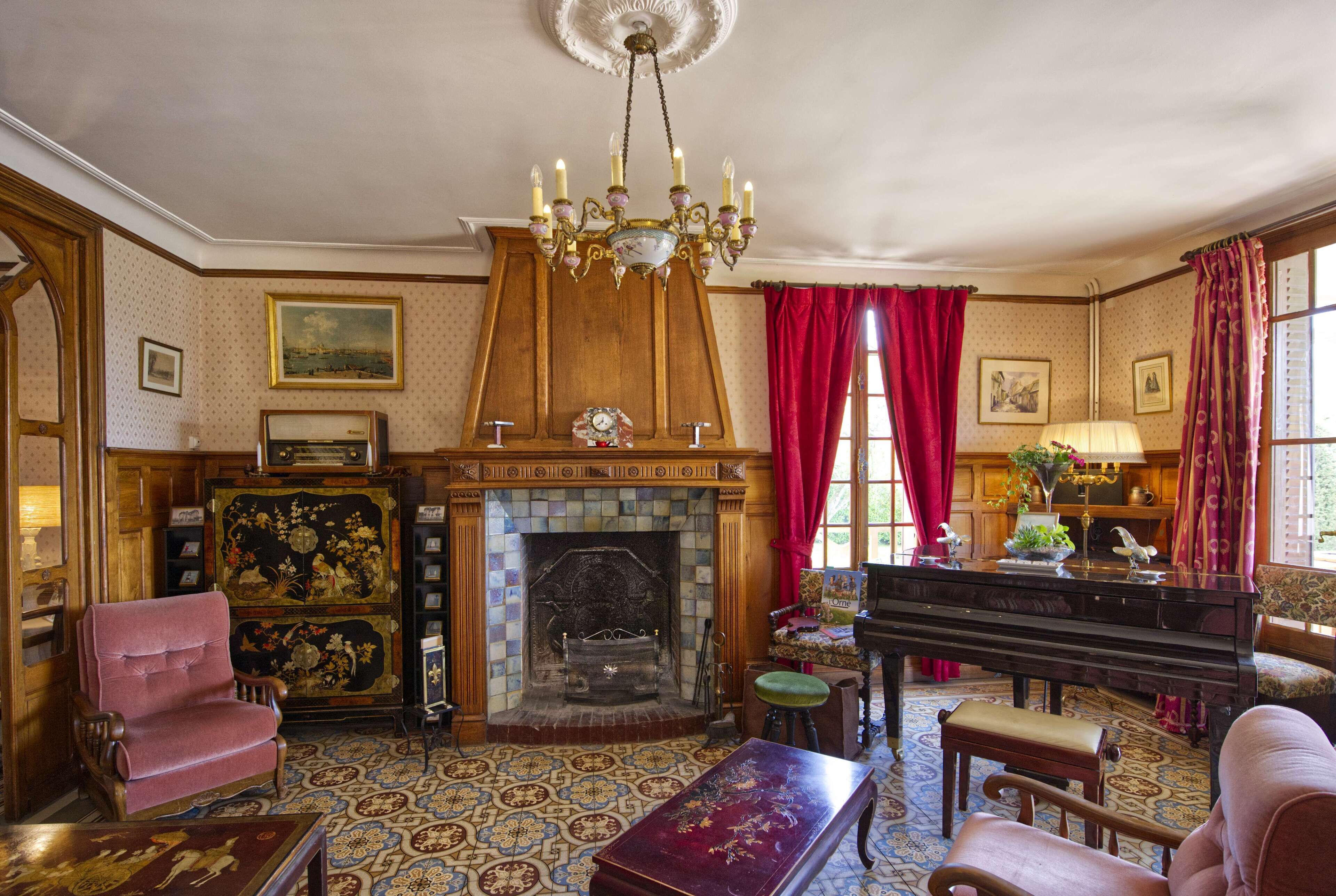 A room with a fireplace, a piano, and a red curtain.
