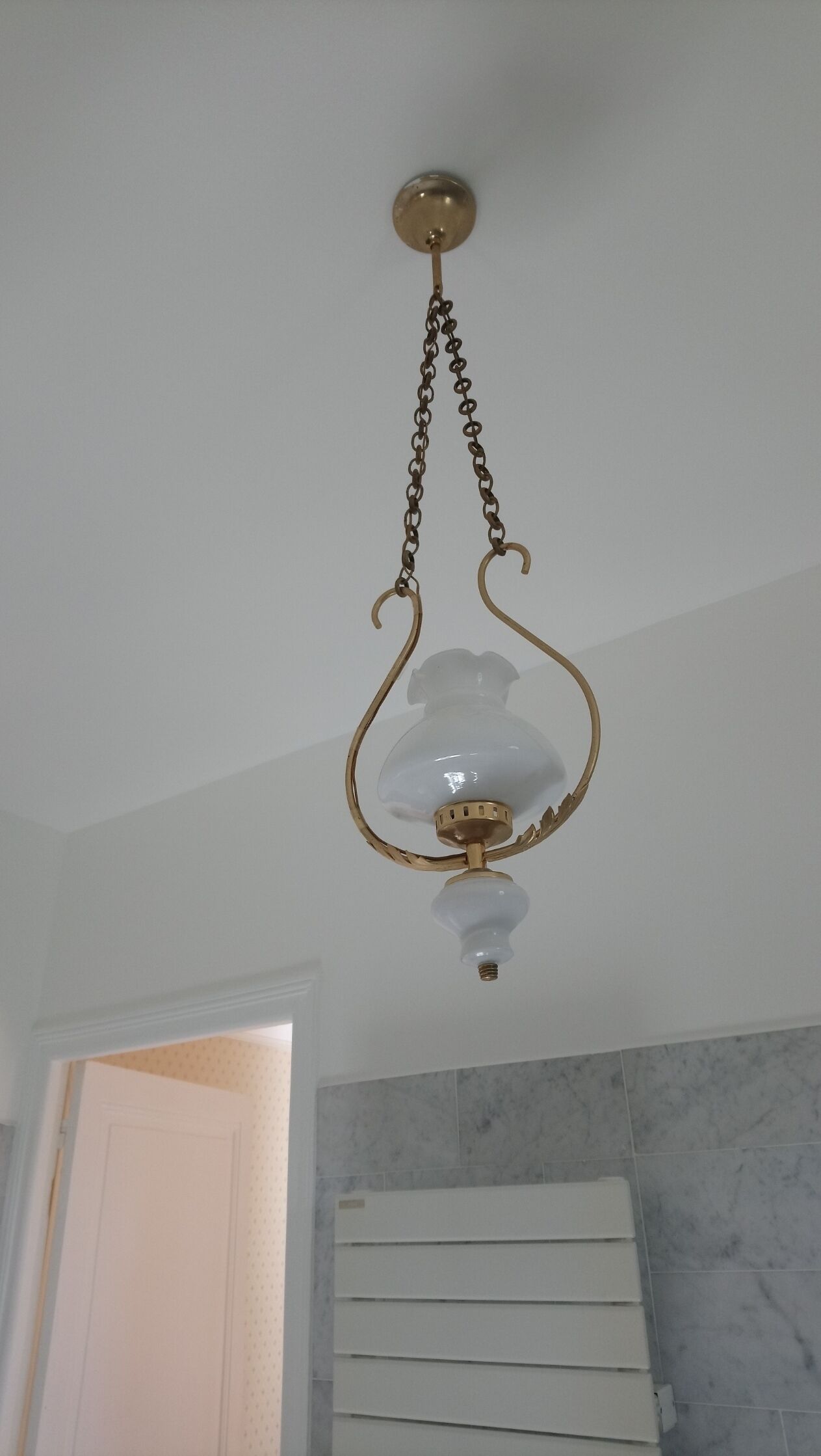 Un luminaire fixé au plafond, doté d’un abat-jour en verre et d’une finition en laiton.
