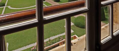Vista a través de una ventana que muestra un jardín cuidado y un cielo nublado.
