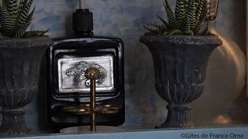 A shelf with a globe, a pink vase, a potted plant, a black perfume bottle, and two potted plants.