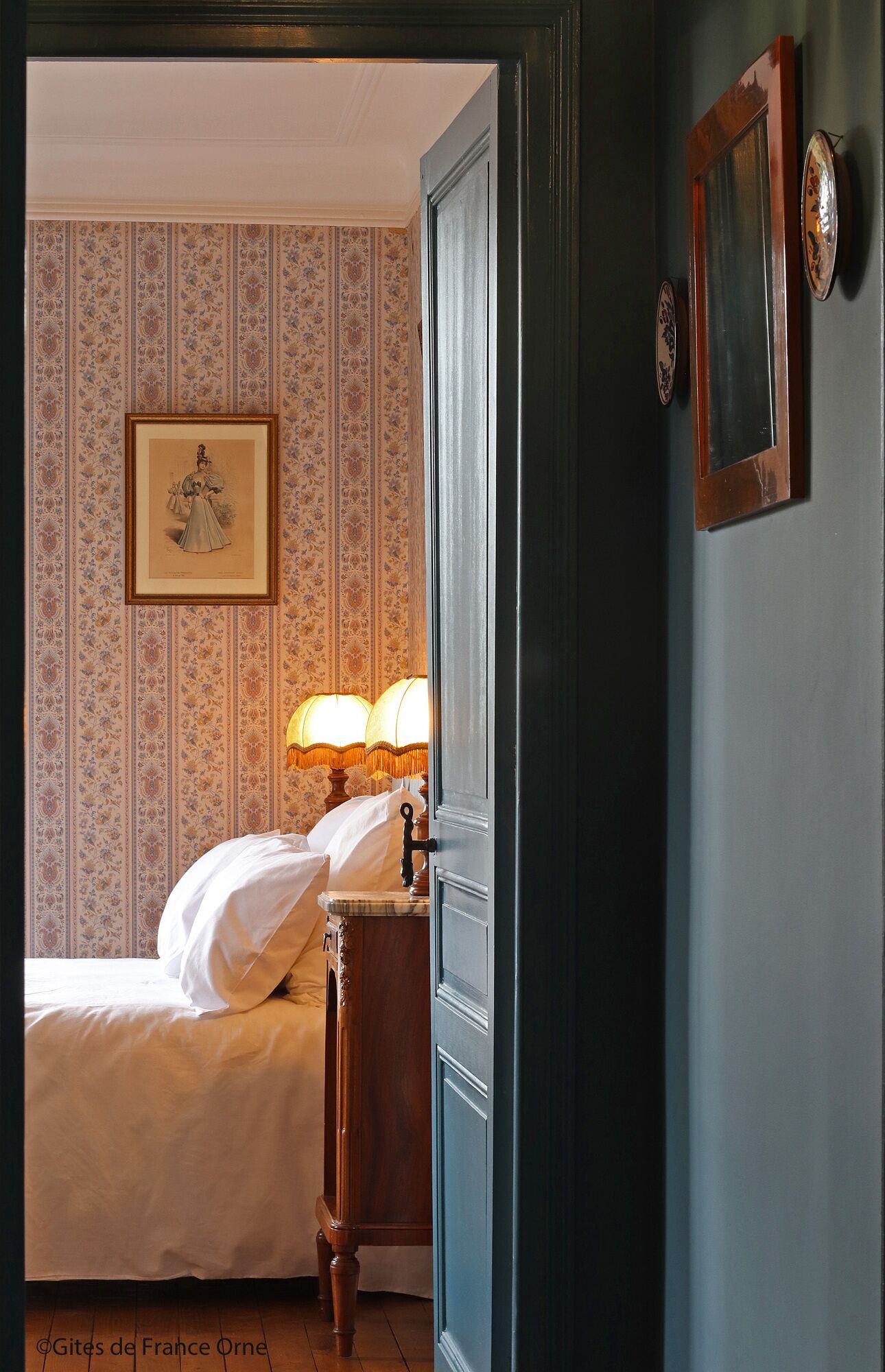 Un dormitorio con una cama, una mesita de noche con una lámpara y un cuadro enmarcado en la pared.