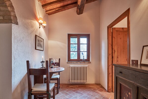 A cozy room with a wooden table, chairs, a window with a view, a radiator, and a wooden door.