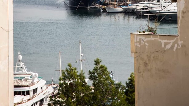 A large yacht docked at a marina with a cityscape in the background. - Amazing apartment with view (Piraeus)