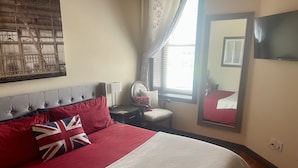 A bedroom with a large bed, a chair, a bedside table, a TV, and a window with curtains. - Contemporary apartment on the square! (Neosho)