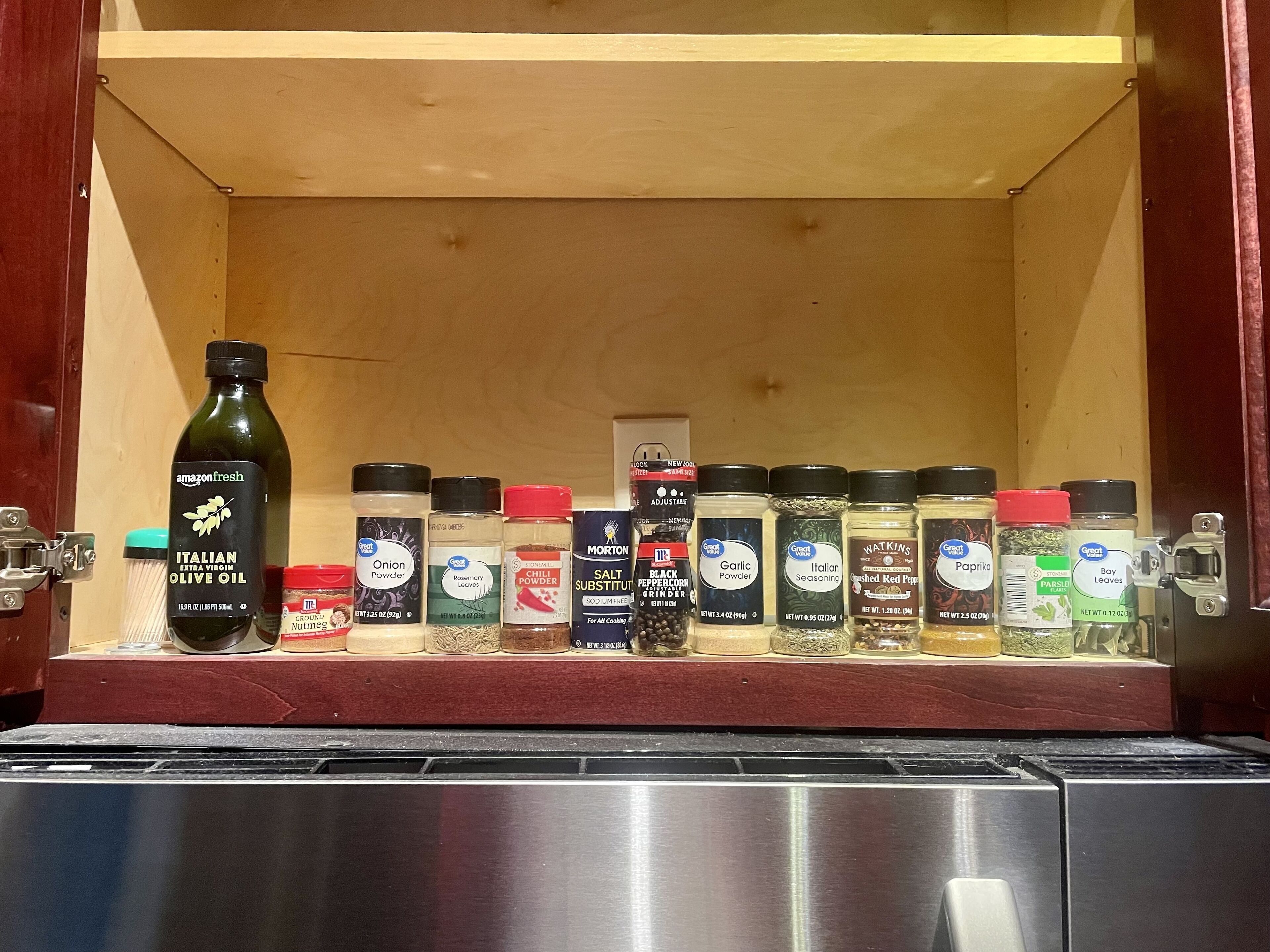A spice rack with various seasonings and a bottle of olive oil.