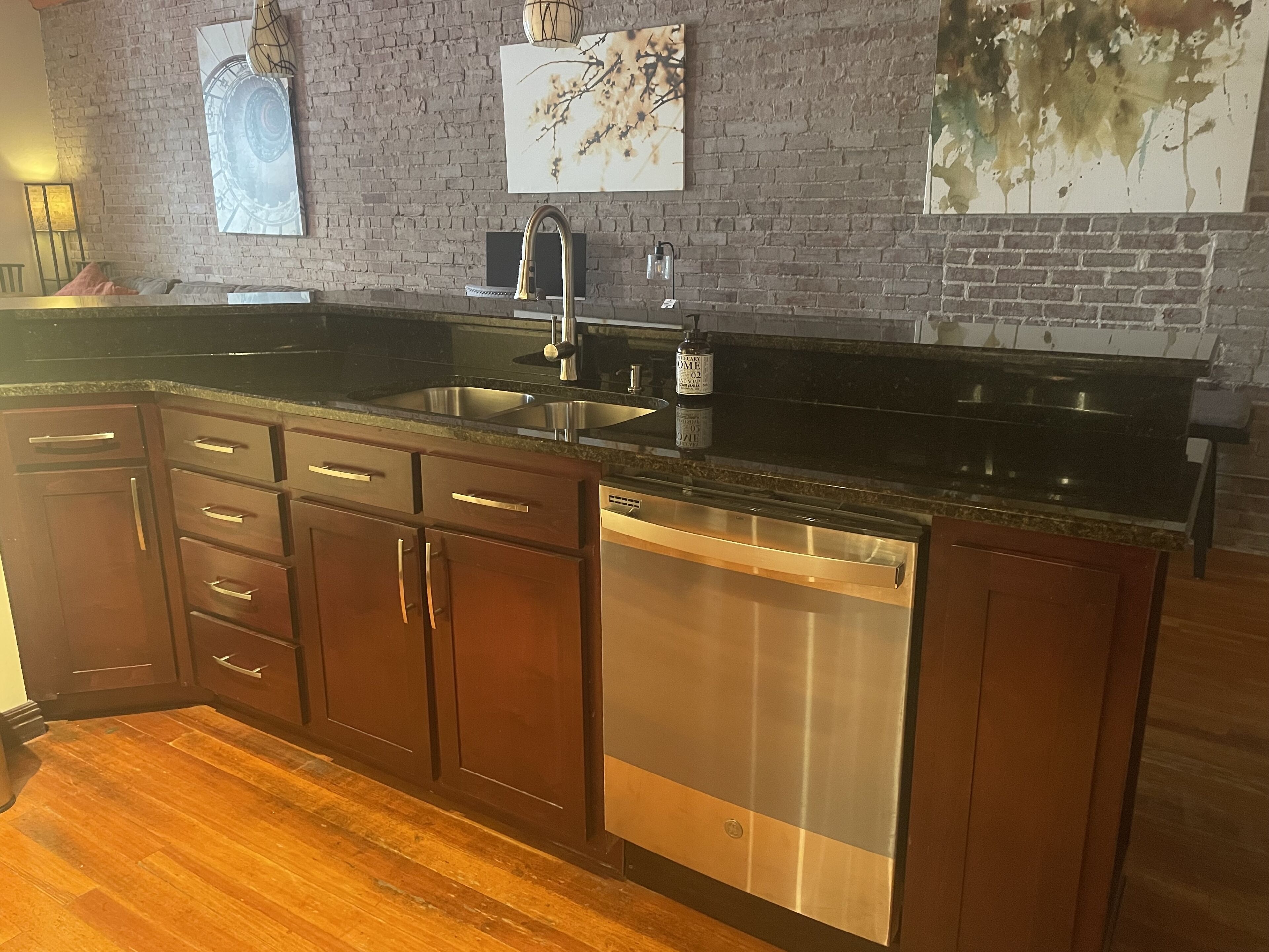 A kitchen with wooden cabinets, a stainless steel sink, and a dishwasher.
