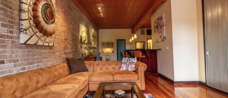 A living room with a wooden ceiling, a brick wall, and a sofa.