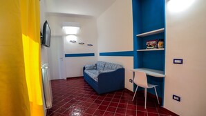 A room with a blue sofa, a white chair, and a shelf with decorative items. - Independent house with access to a panoramic lemon grove on the Amalfi Coast! (Scala)