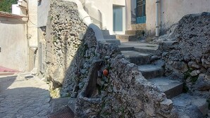 A stone staircase leading to a building with a rustic appearance, featuring a mix of stone and plaster walls, a satellite dish, and a small window with a shutter. - Independent house with access to a panoramic lemon grove on the Amalfi Coast! (Scala)