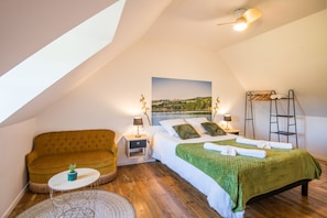 A cozy bedroom with a bed, a sofa, a small table, and a ladder.