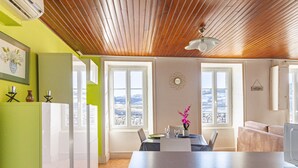 A modern kitchen with a dining area, wooden ceiling, and large windows. - Le Barry - Studio avec jardin (Murat)
