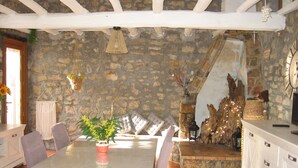 Un coin repas avec un mur en pierre, un escalier en bois et une horloge.