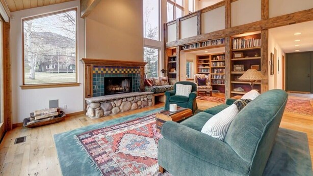 A spacious living room with a fireplace, a large window, and a high ceiling. - The Silver Spur | 5BR Cabin, Walk to PCMR (Park City)