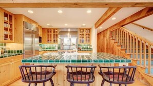 A kitchen with wooden cabinets, a tiled island, and a staircase. - The Silver Spur | 5BR Cabin, Walk to PCMR (Park City)