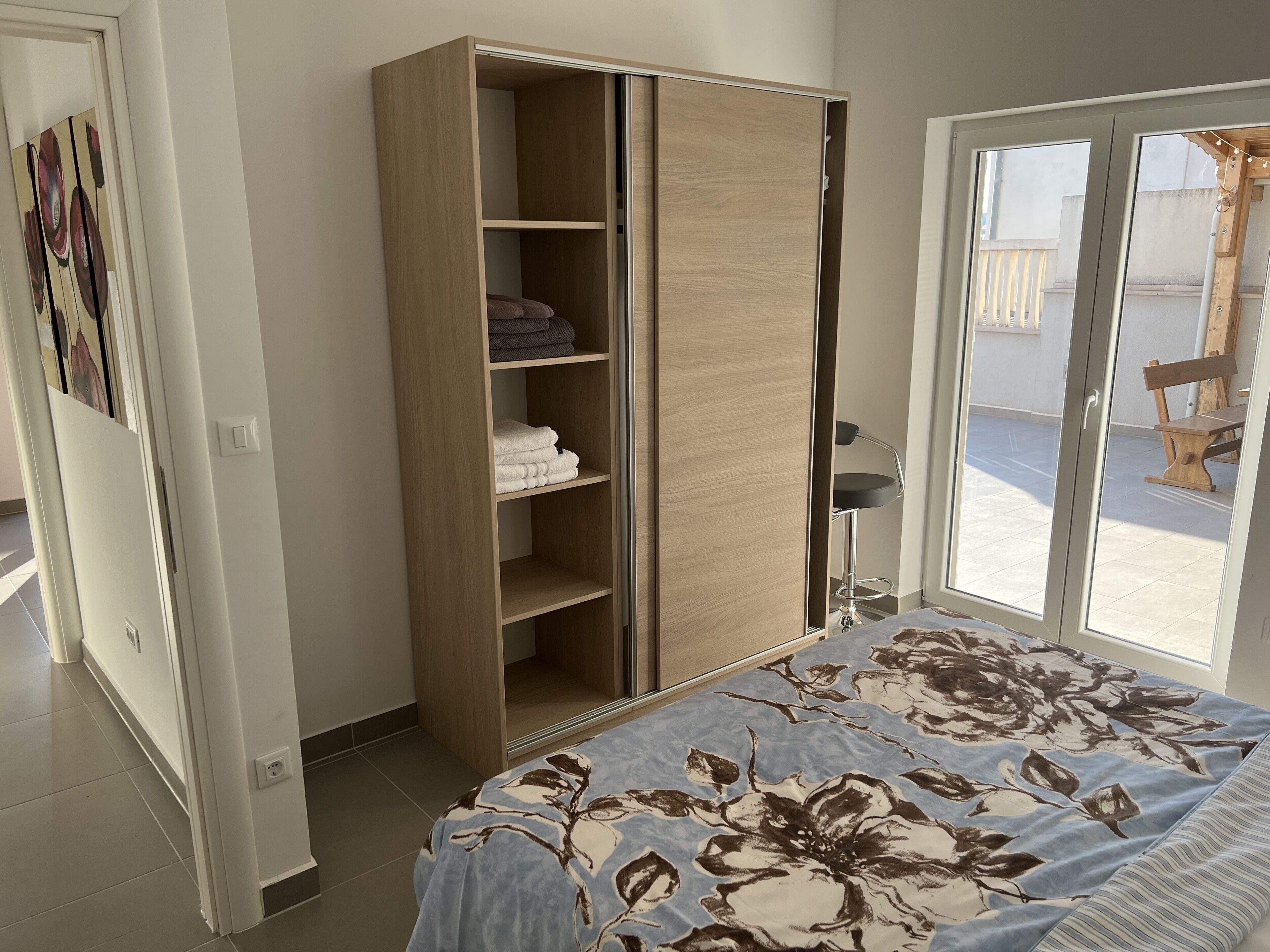 Ein Schlafzimmer mit einem Bett, einem Kleiderschrank und einer Schiebetür zum Außenbereich.