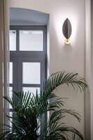 En døråbning med sandblæst glas, en vægmonteret lampe og en potteplante.