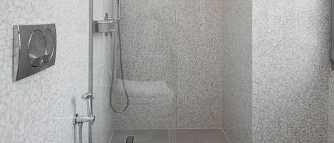 Un baño moderno con ducha envuelta en vidrio, un lavamanos blanco y una toalla sobre la encimera.