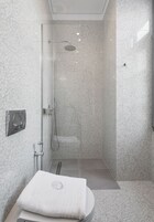 Un baño moderno con ducha envuelta en vidrio, un lavamanos blanco y una toalla sobre la encimera.