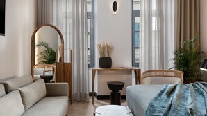 Una habitación de hotel moderna con sofá, cama, escritorio y espejo.