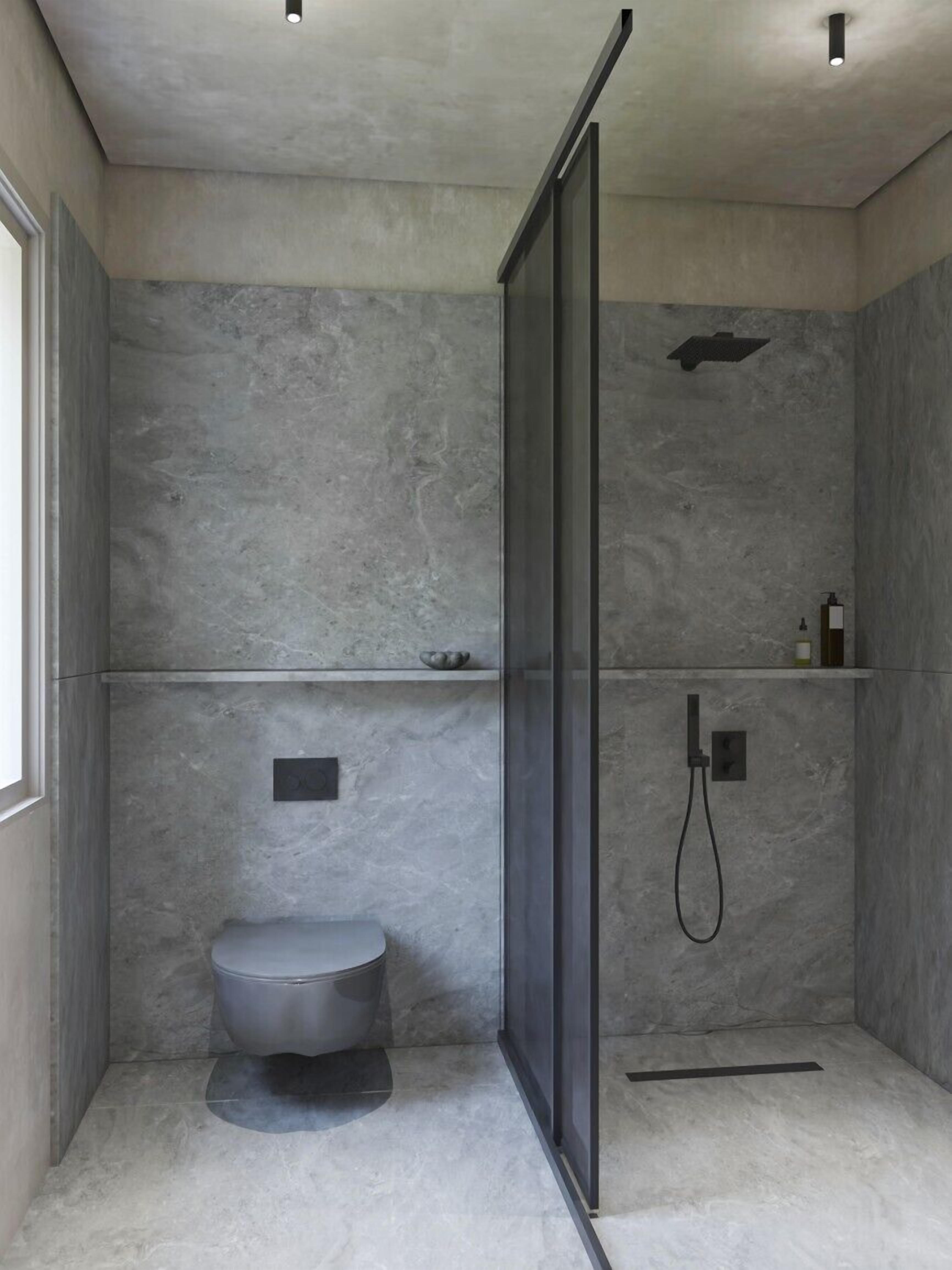 A modern bathroom with a shower, toilet, and a glass partition.