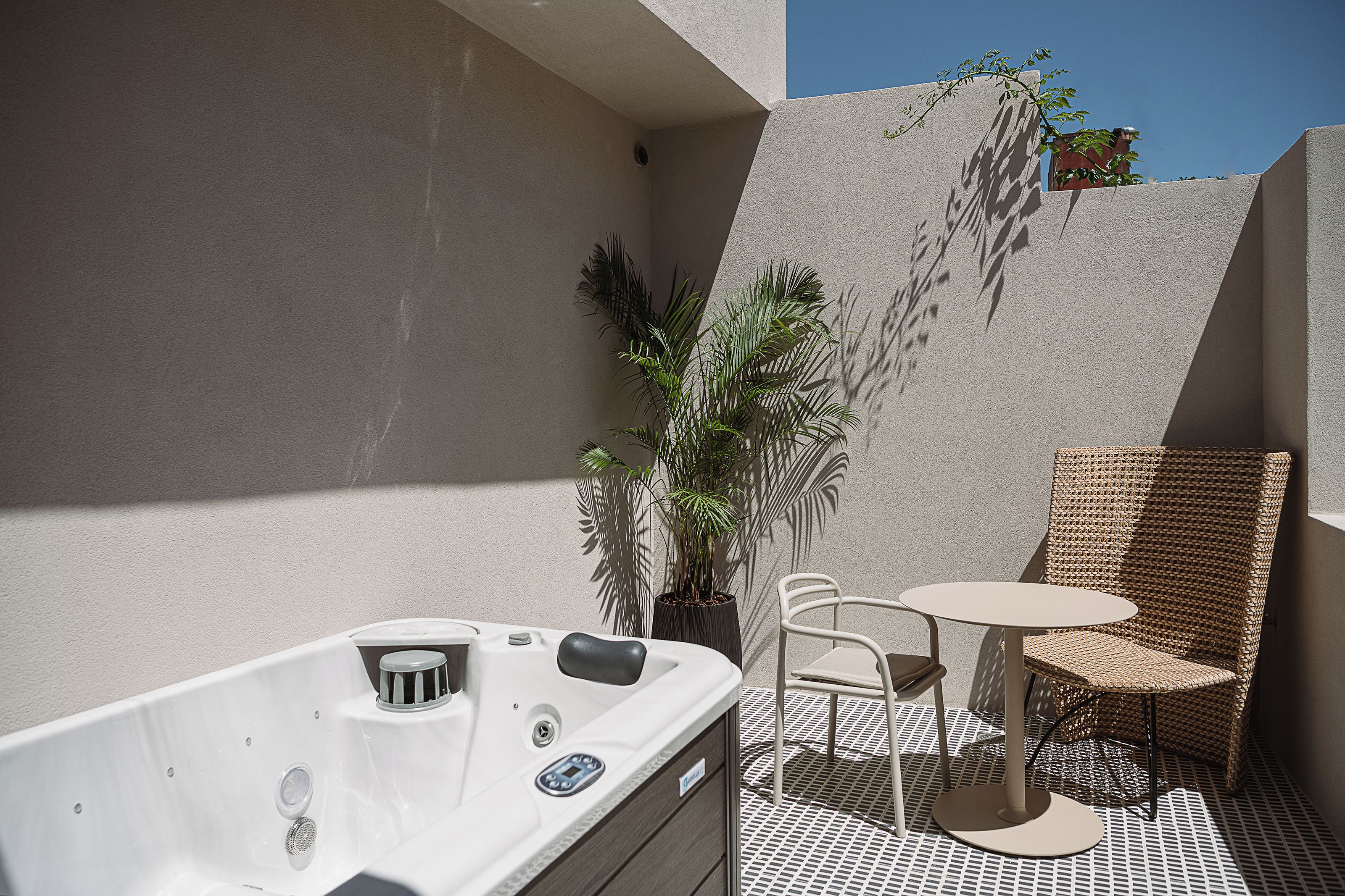 A small outdoor seating area with a table and chairs, a hot tub, and potted plants.