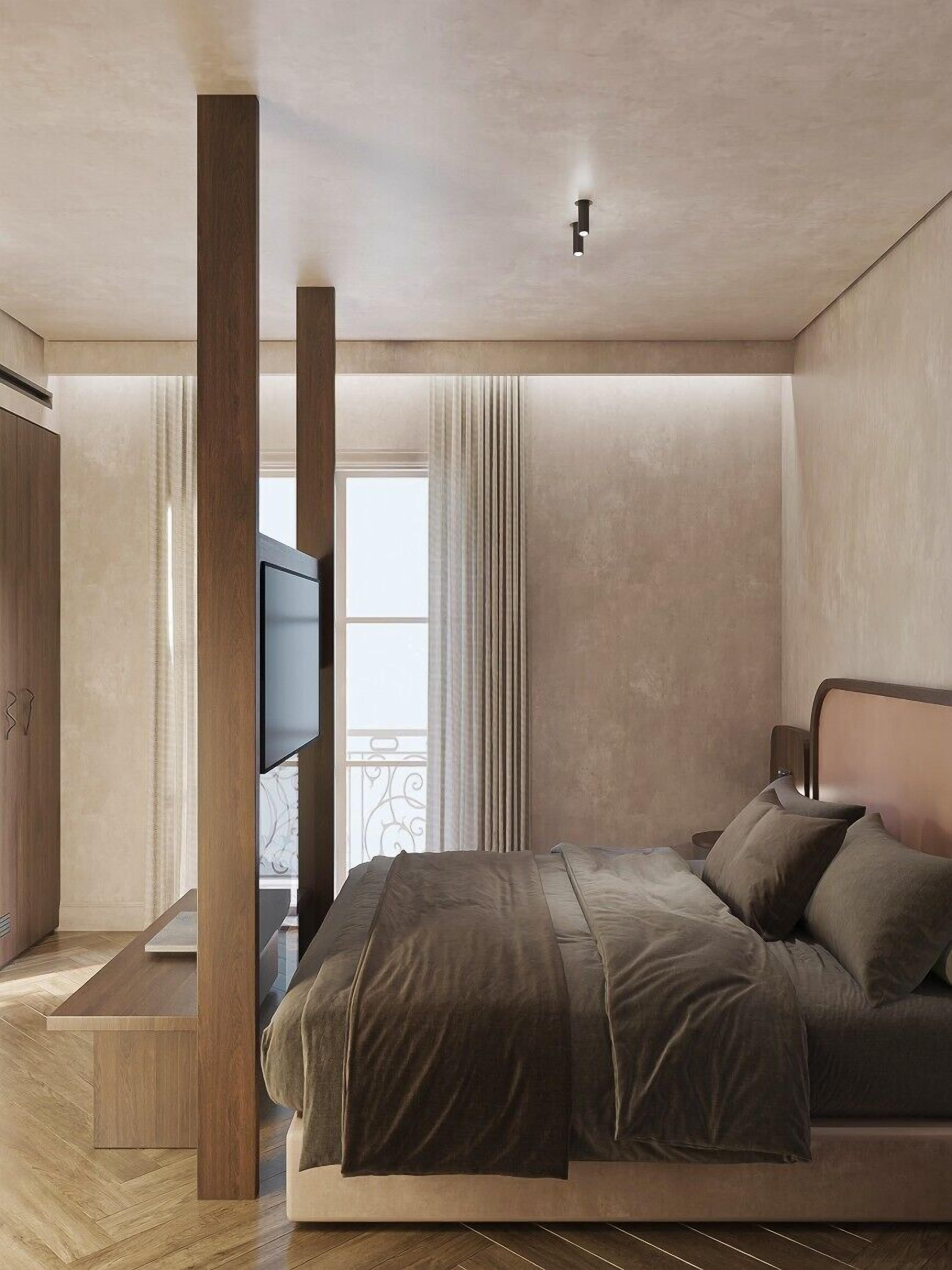 A modern bedroom with a large bed, a TV, and a wooden column.