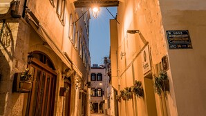 Una calle estrecha flanqueada por edificios, un pasaje abovedado y un farol.