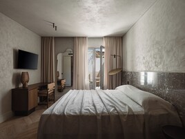 Une chambre à coucher avec un lit, un bureau, une chaise, une télévision et une fenêtre avec des rideaux.
