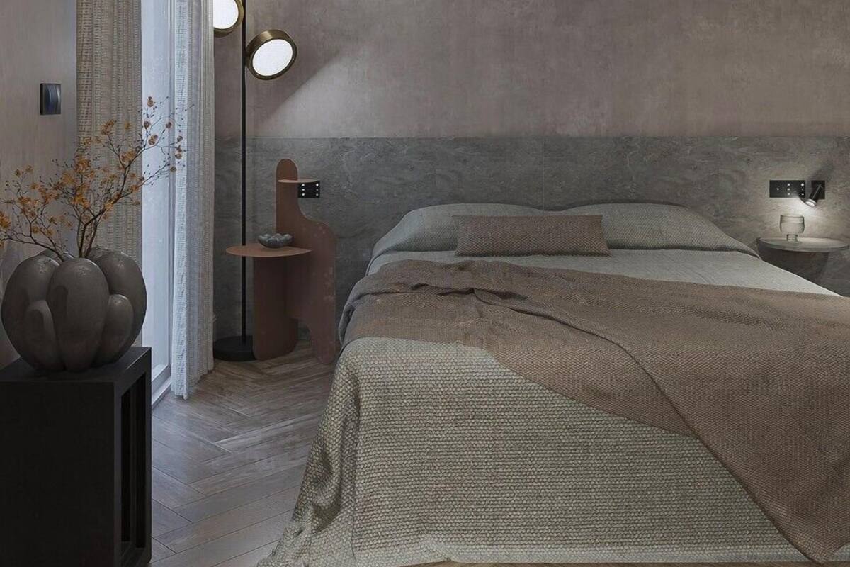 A modern bedroom with a large bed, a bedside table, a floor lamp, and a vase with flowers.