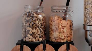 A breakfast buffet with jars of granola and nuts, bowls of yogurt, and a coffee machine.
