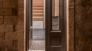 Una entrada de paredes de piedra con una puerta de madera y una lámpara pequeña en la parte superior.